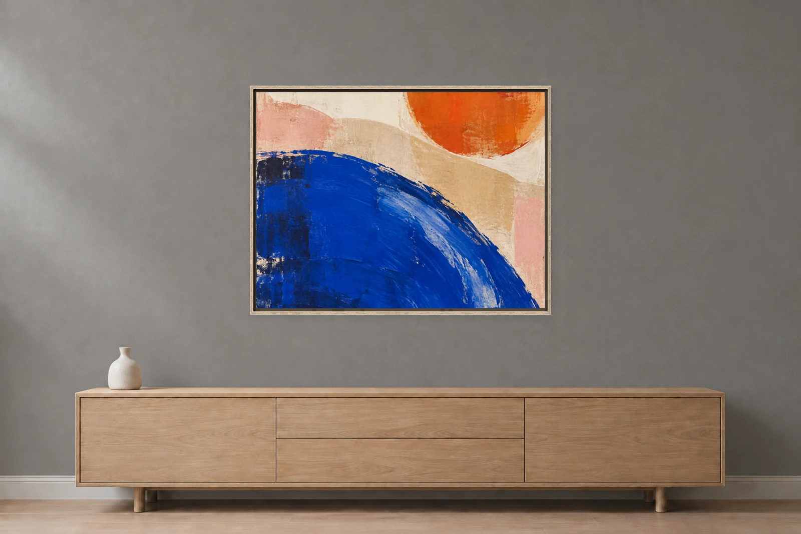 Eichenrahmen mit farbigem Leinwandbild vor einer steingrauen Wand über einem Sideboard – fotobasierte Raumvisualisierung.